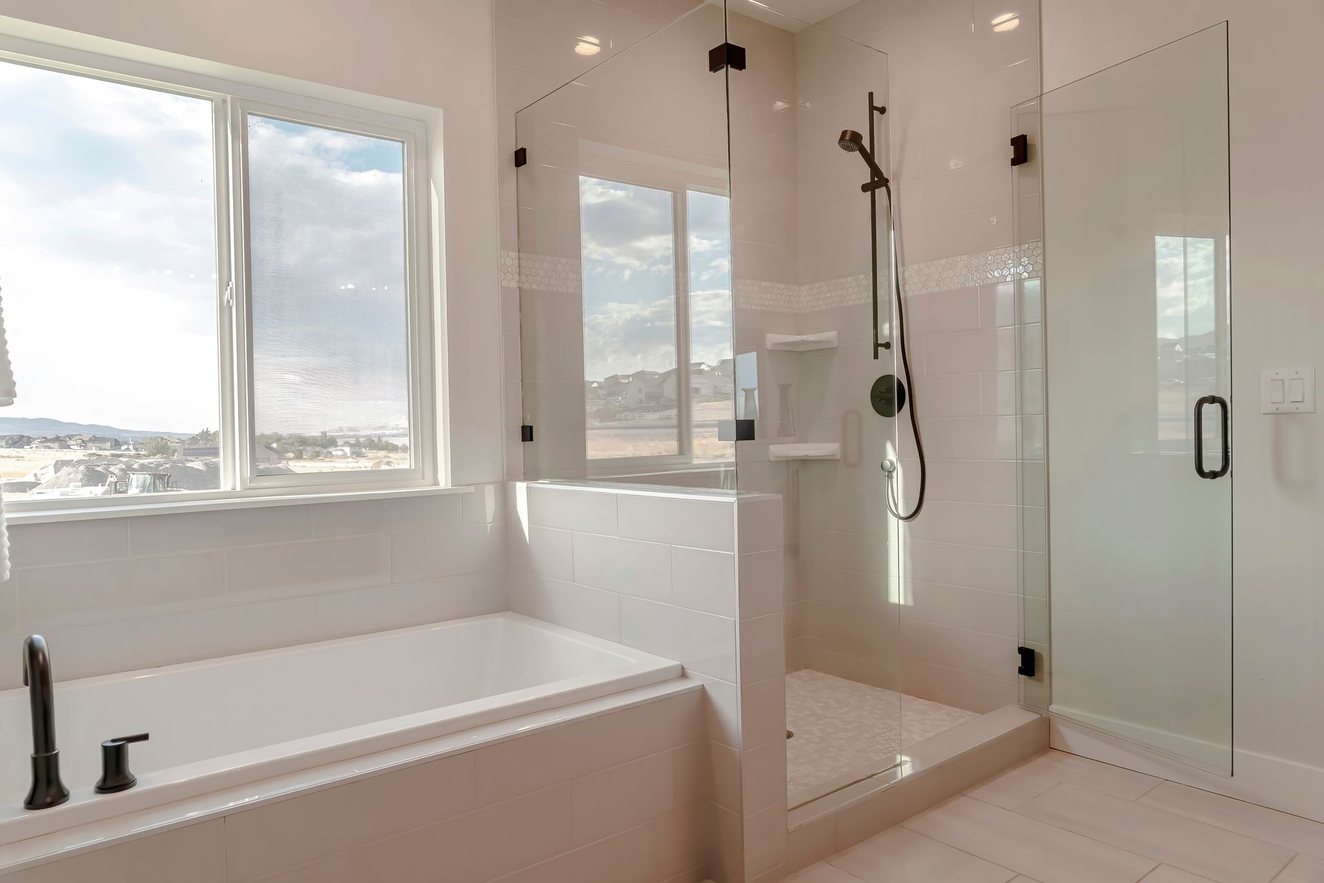 Modern bathroom with bathtub, glass shower, and large window overlooking the water