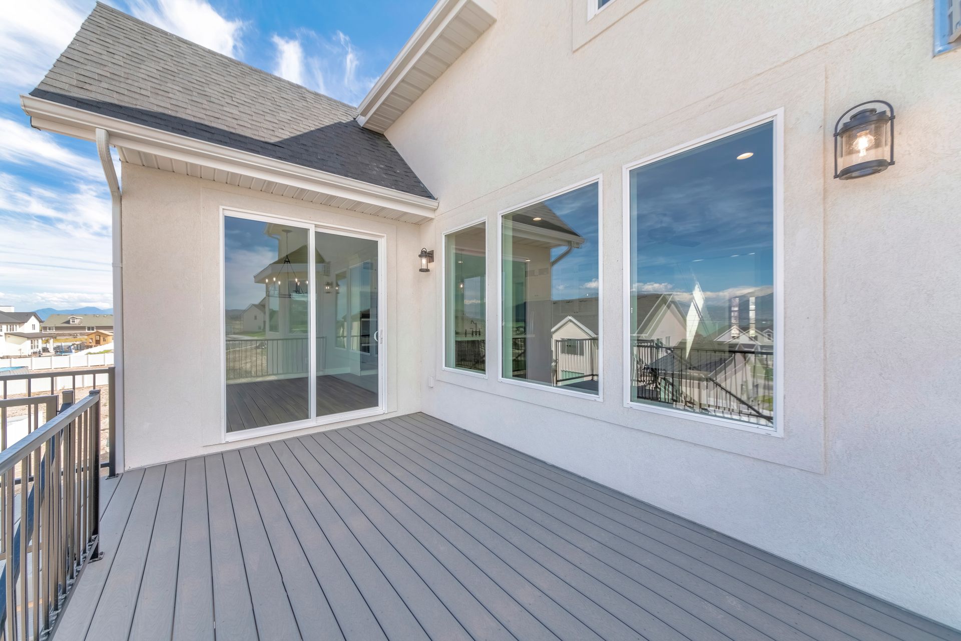 Spacious rooftop deck with sliding glass doors, windows, and a view of nearby buildings and water
