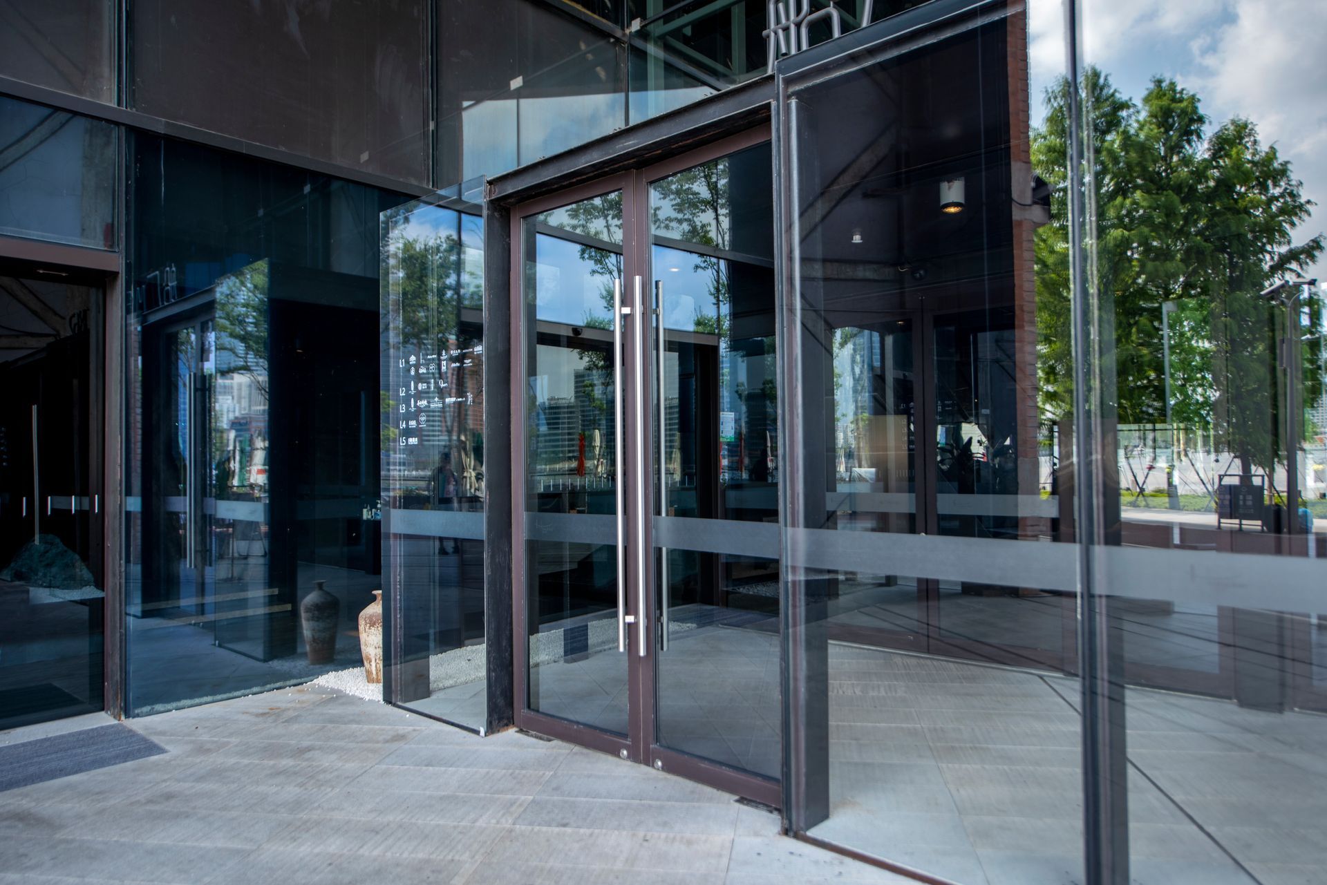 Glass entrance doors to a modern building with reflective windows and pavement outside