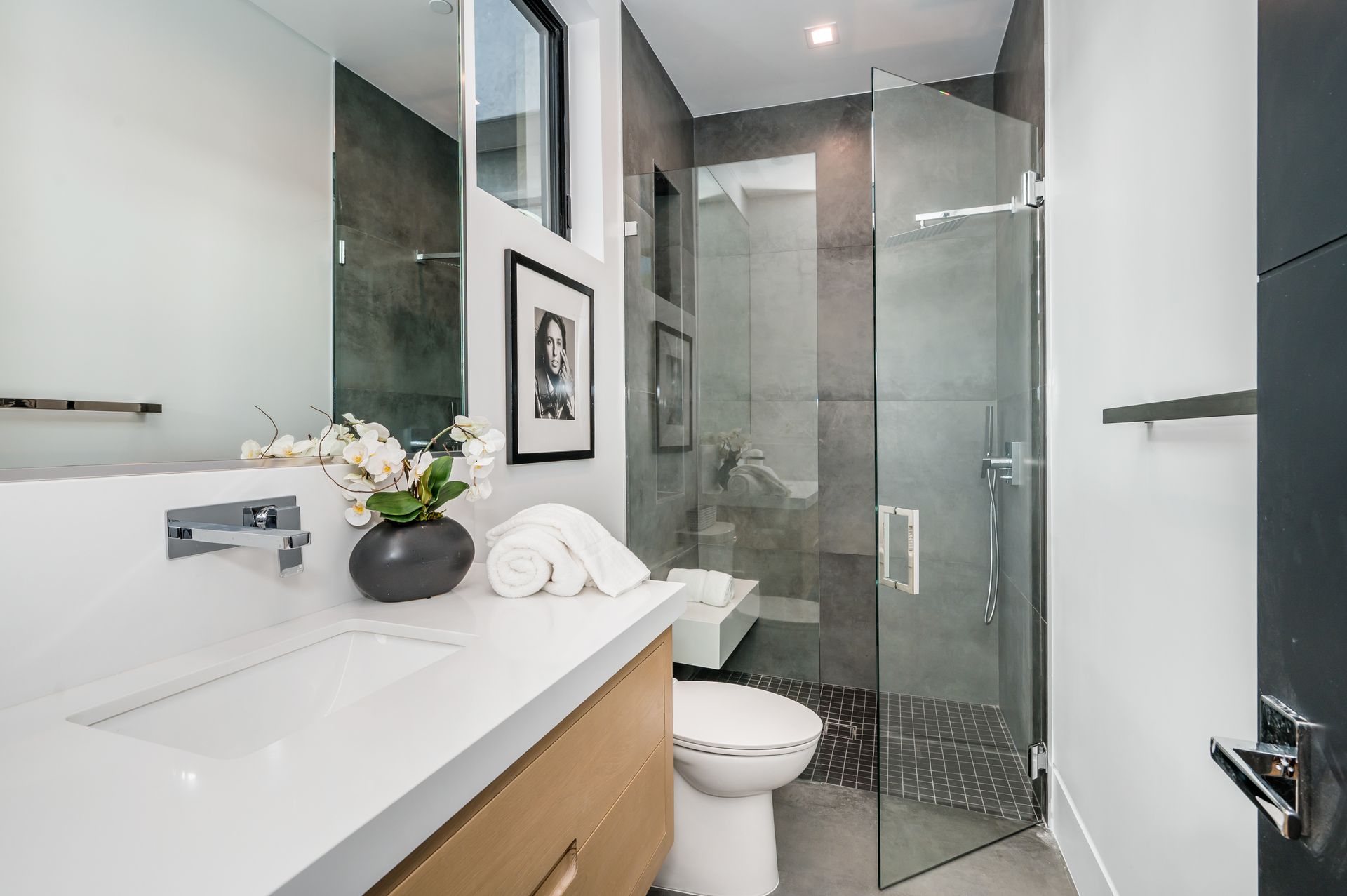 Modern white bathroom with vanity, mirror, glass shower, and toilet