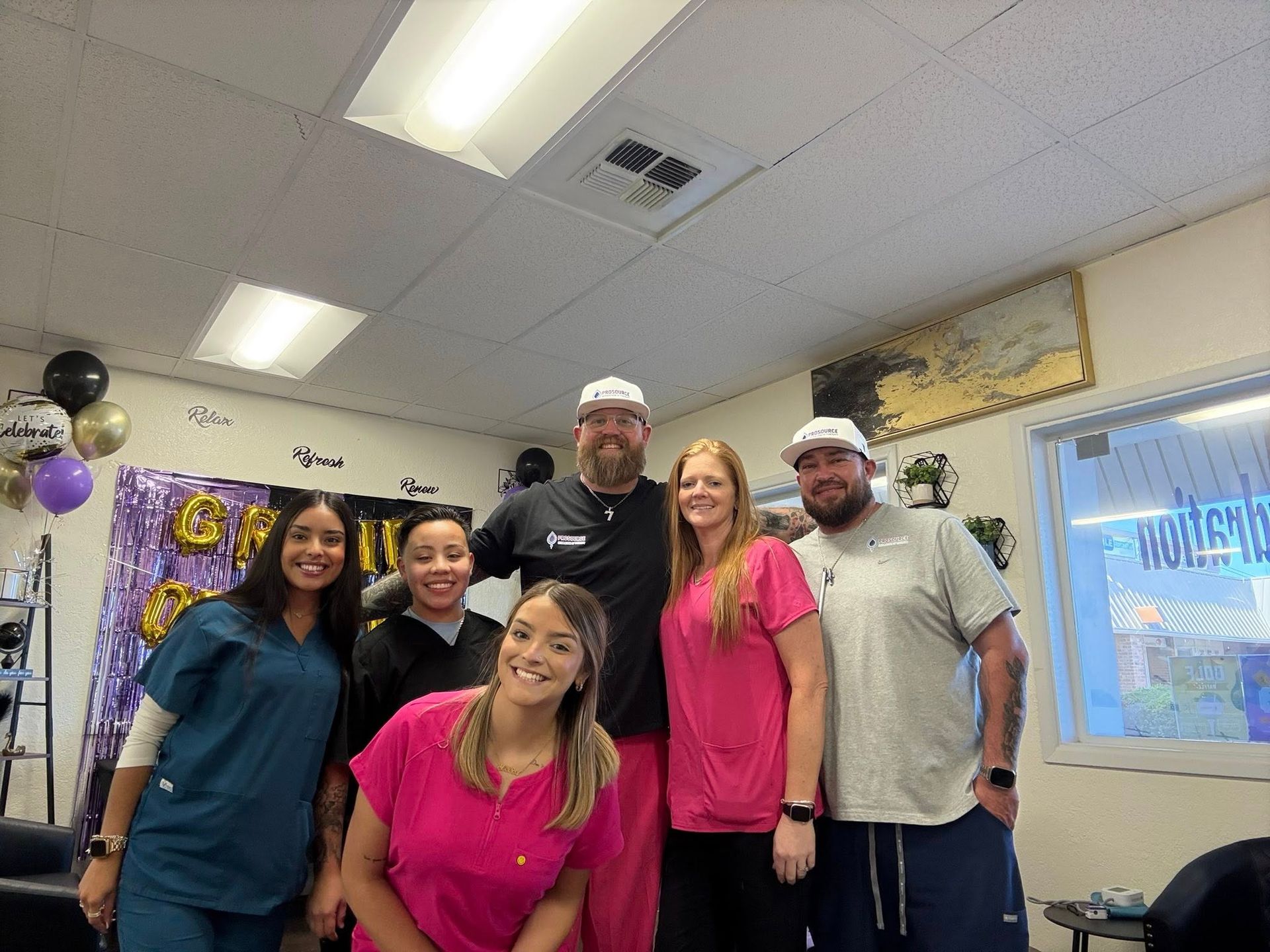 Group of six people smiling in a decorated room, balloons, 