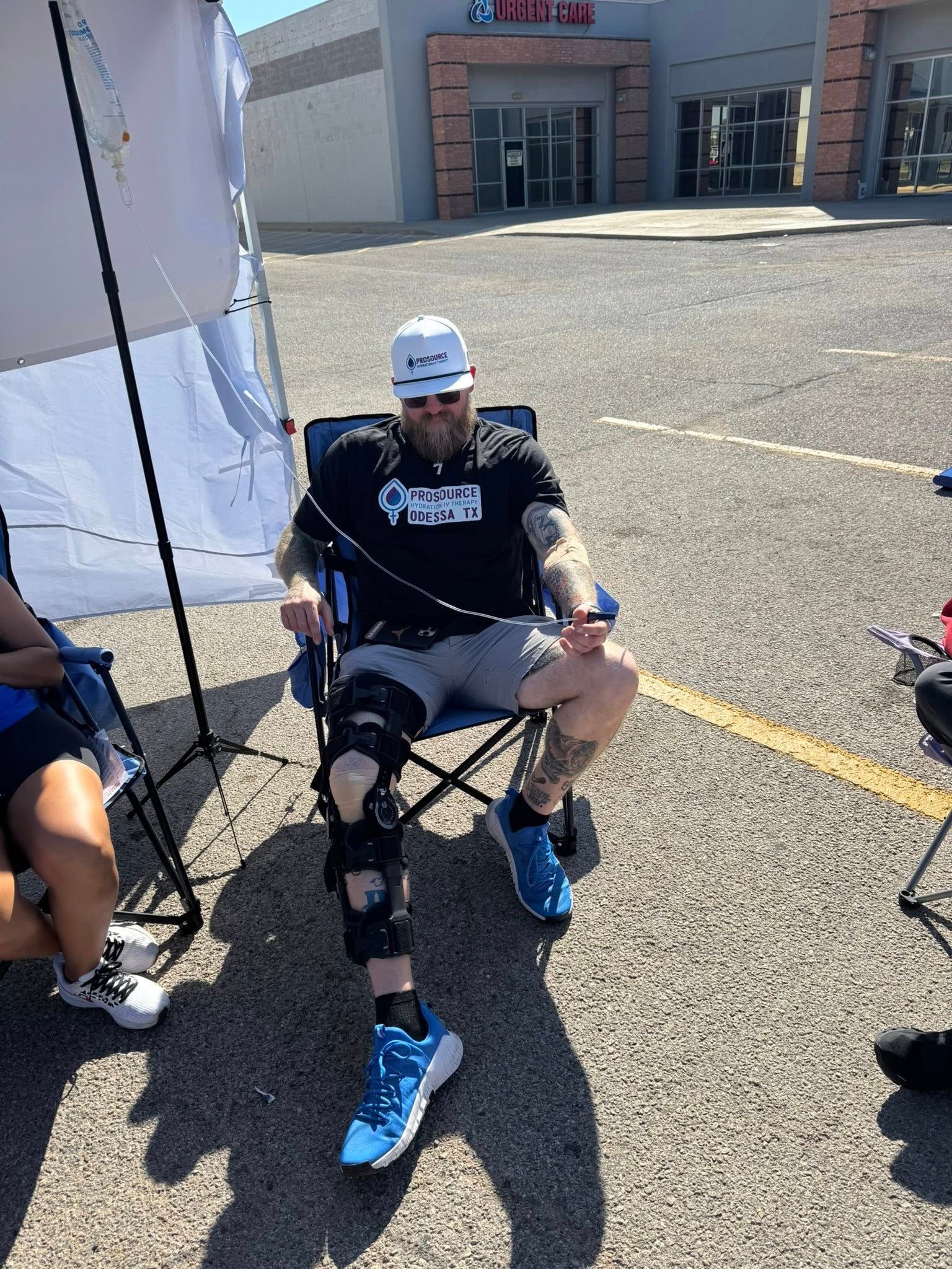 Man seated in chair with leg brace outdoors.