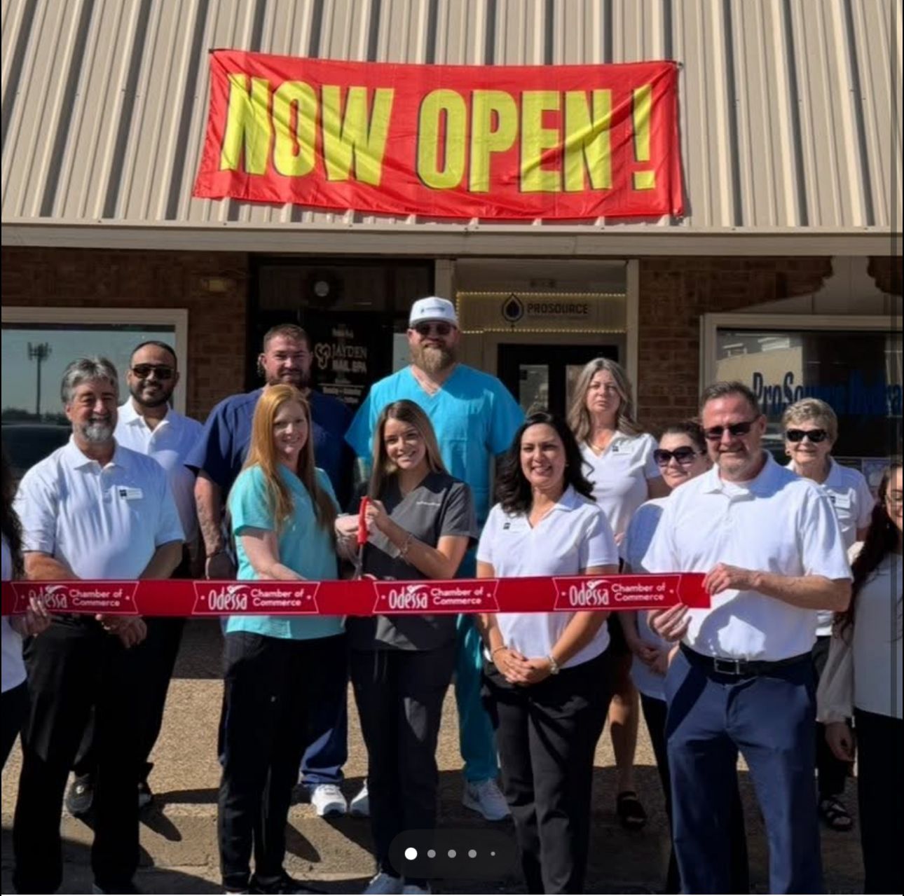 People cutting a ribbon in front of a building with a 