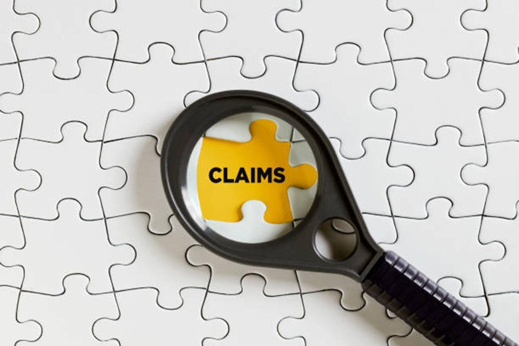 A magnifying glass on a puzzle l Workers Comp Attorney Greenville SC, Hayes Law Firm