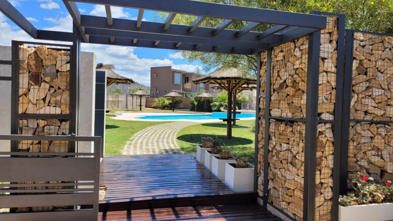 Arco que conduce a una zona de piscina; paredes de piedra y madera flanquean la abertura.