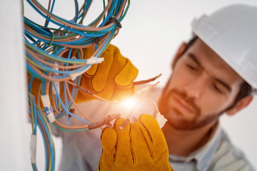 An electrician is working on a wall with wires.