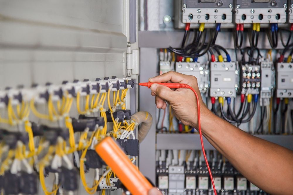 A person is working on an electrical box with a multimeter.