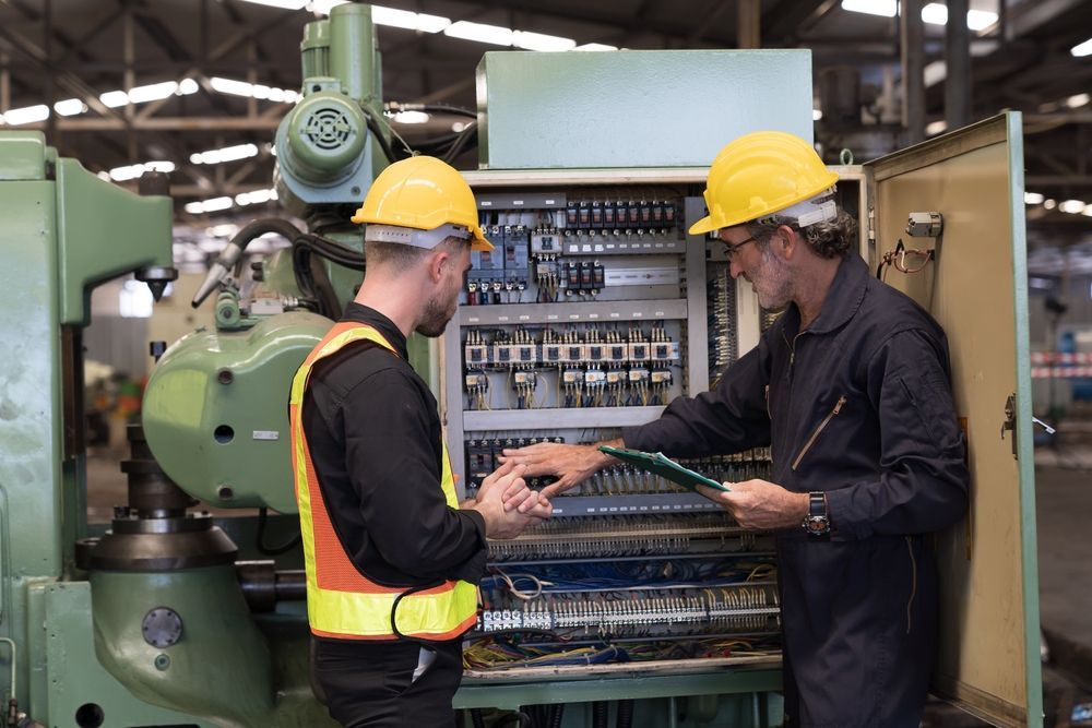 Two men are working on a machine in a factory.