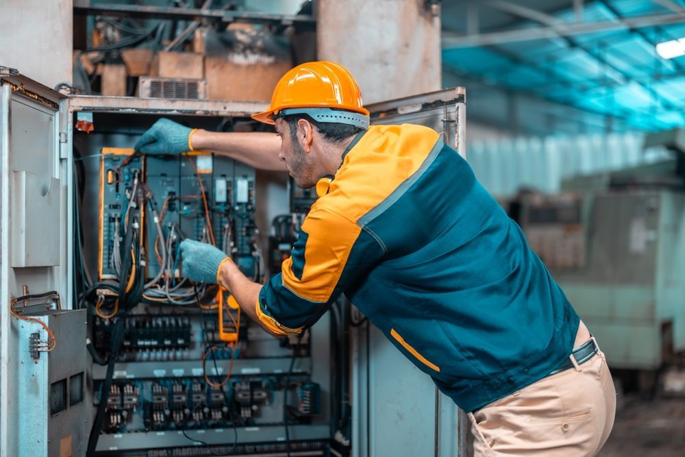 A man is working on an electrical box in a factory.