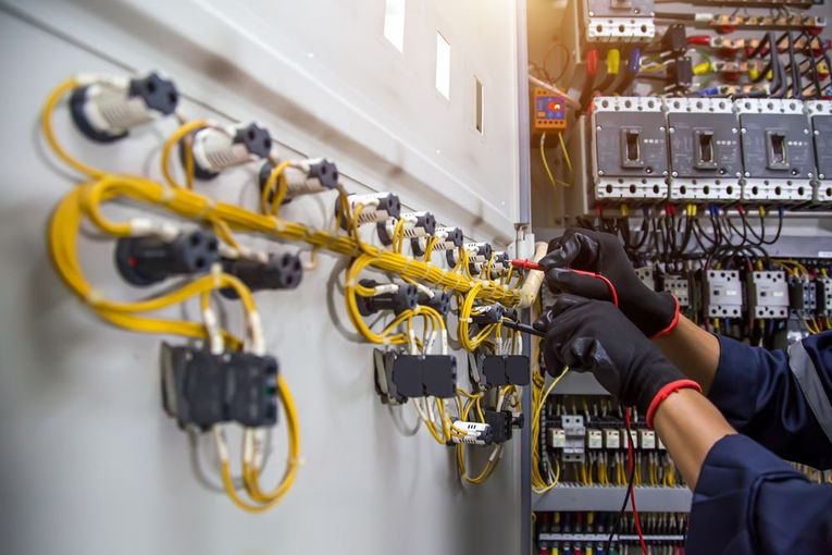 An electrician is working on an electrical panel in a factory.