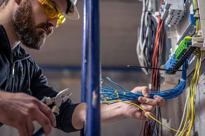 An electrician is working on a wall with wires.