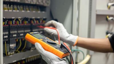 A person is using a multimeter to test a circuit board.