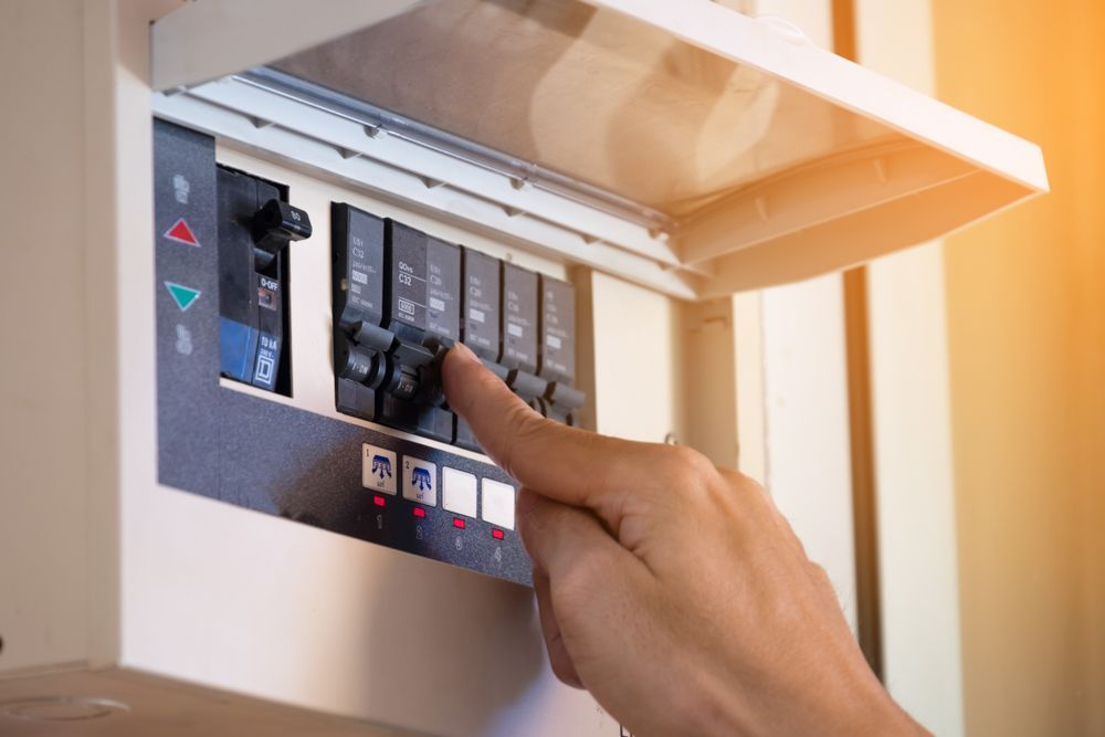 A person is pressing a button on an electrical box.