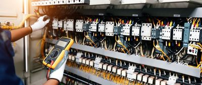 An electrical engineer is working on a electrical panel in an industrial facility.