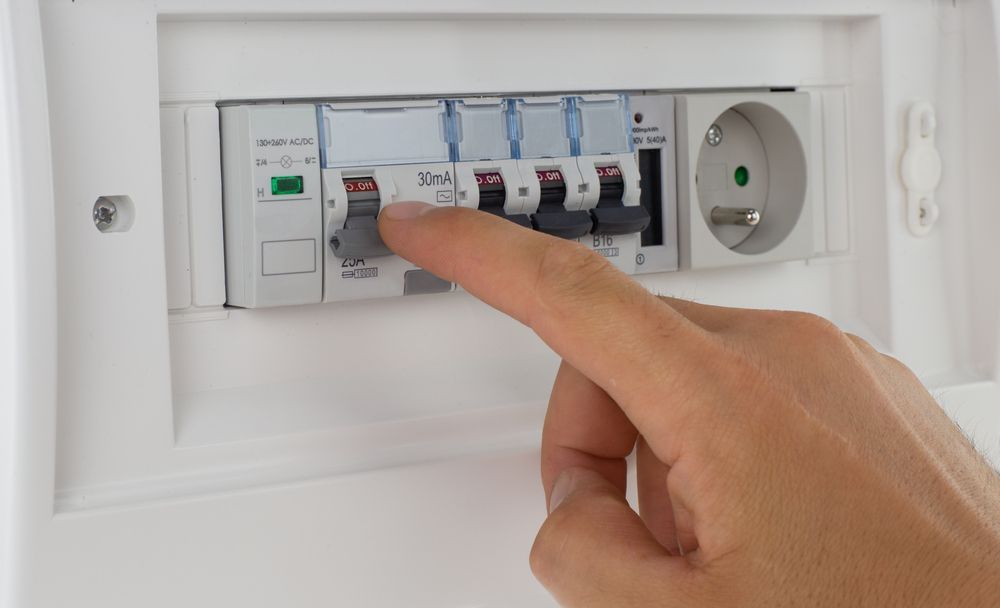 A person is pressing a button in a circuit breaker.