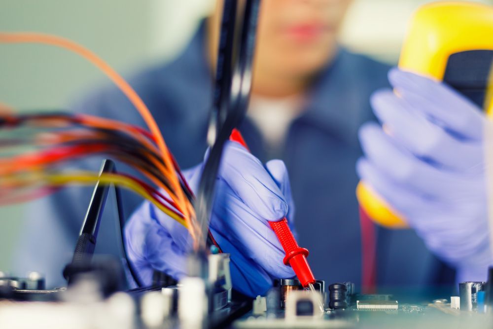 A man wearing purple gloves is using a multimeter.