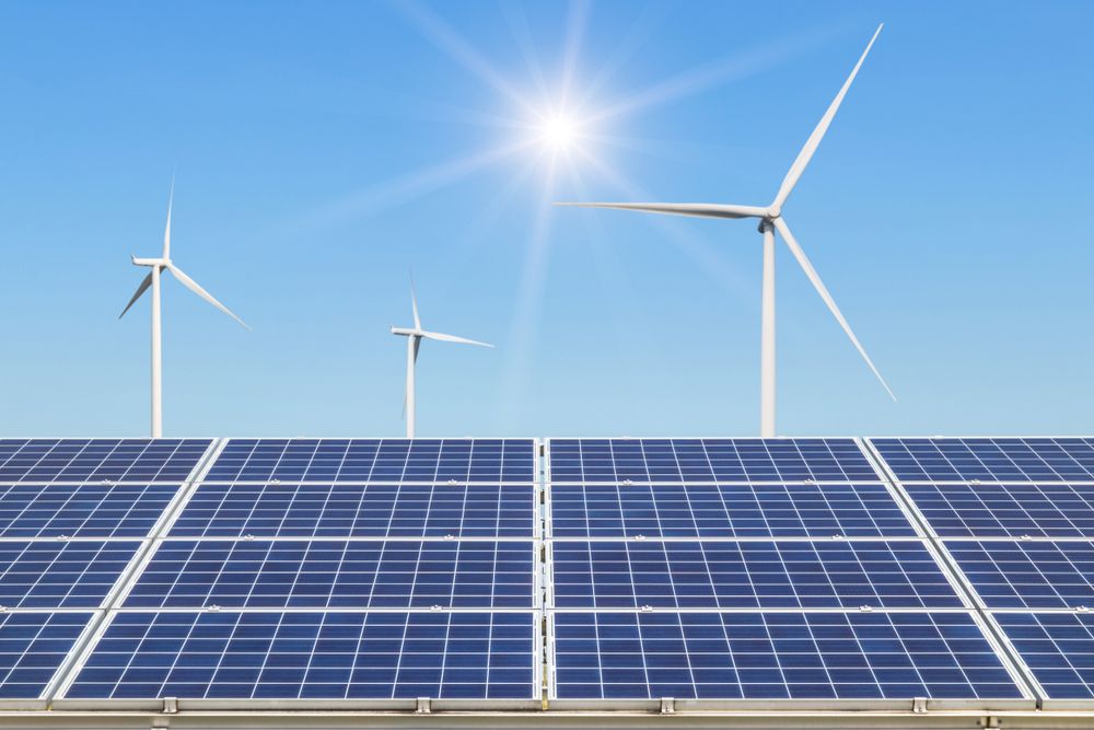 A row of solar panels and wind turbines against a blue sky.