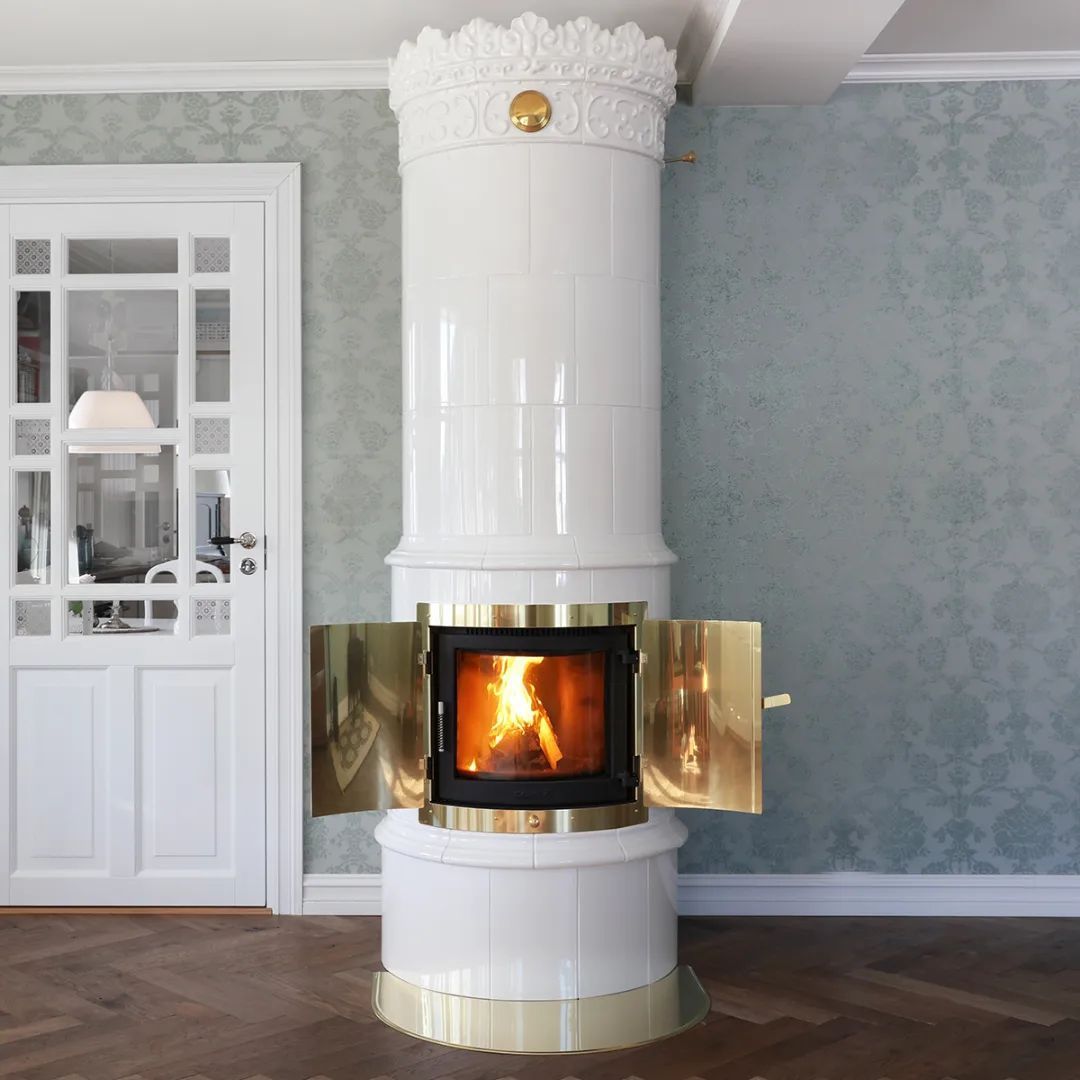 en vit kakelugn med öppen dörr och eld inuti