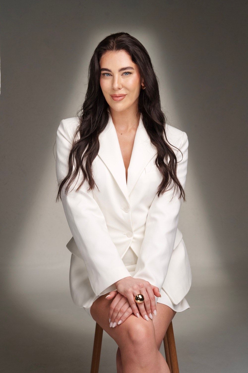 Frau im weißen Kittel hält Spritze und lächelt in die Kamera.