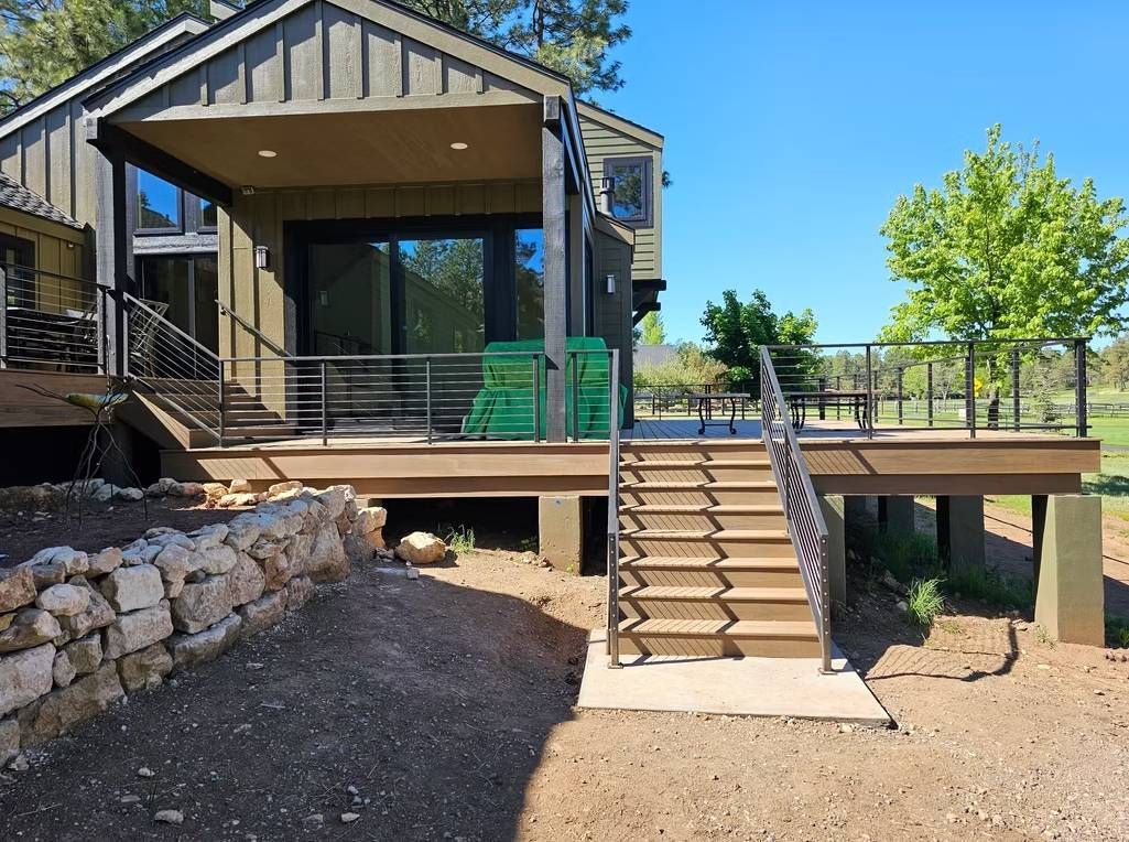 Modern house with a raised deck, stairs, and glass doors in a dry, landscaped yard