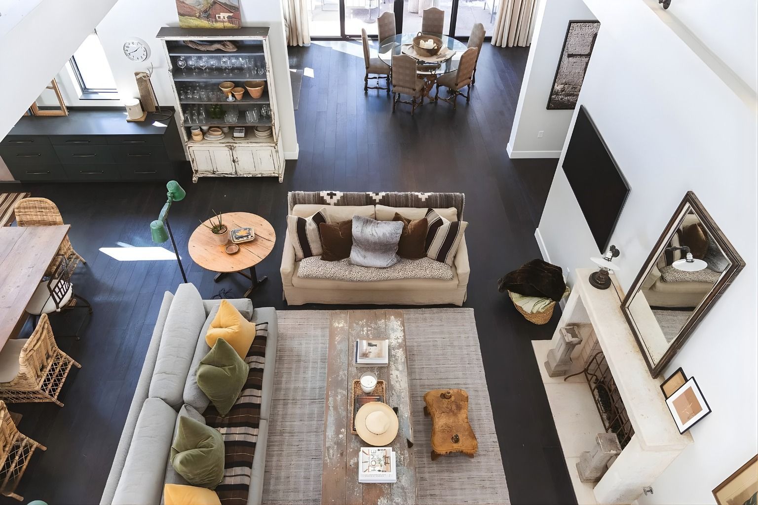 Overhead view of a modern living room with sofas, rug, TV, dining area, and open floor plan.