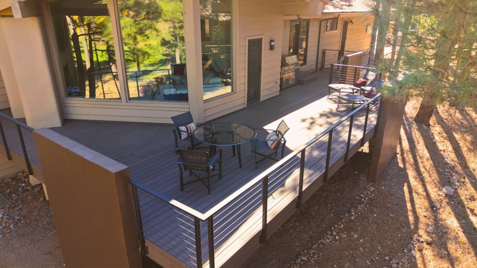 Outdoor patio with metal tables and chairs beside a building, lit by warm sunlight.