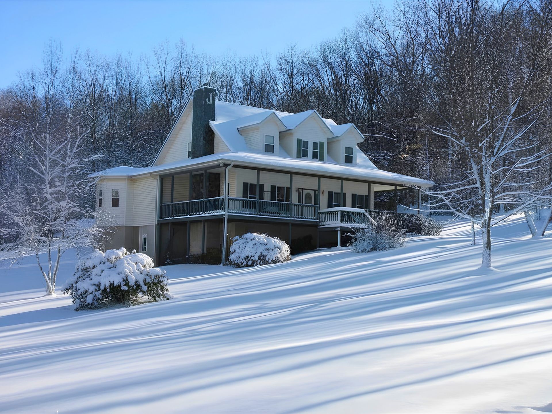 Snow-covered house with porch and dormer windows on a winter day