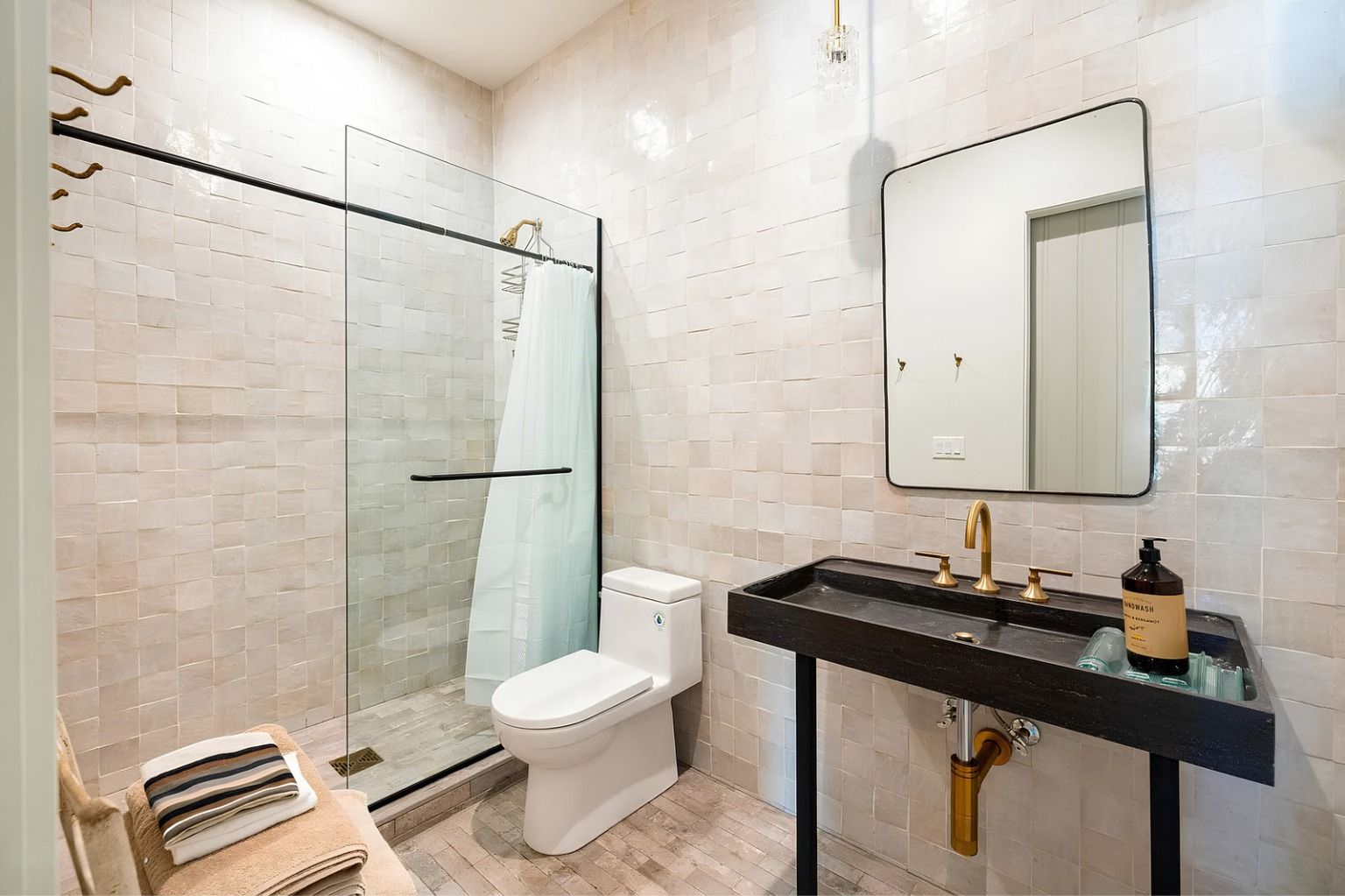 Modern bathroom with glass shower, white toilet, and black vanity under a mirror