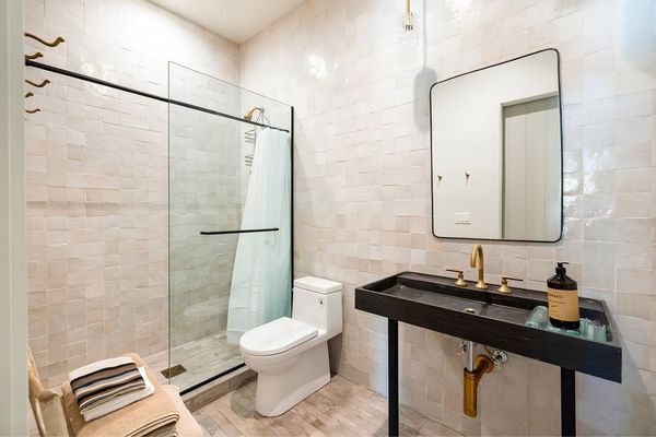 Modern bathroom with glass shower, white toilet, black vanity, and large mirror