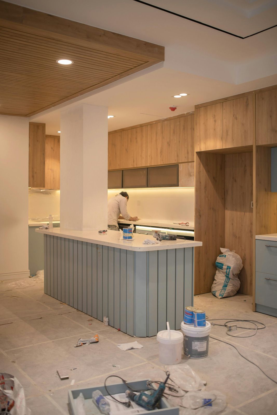 Unfinished kitchen with wood cabinets, blue island, and construction materials on the floor