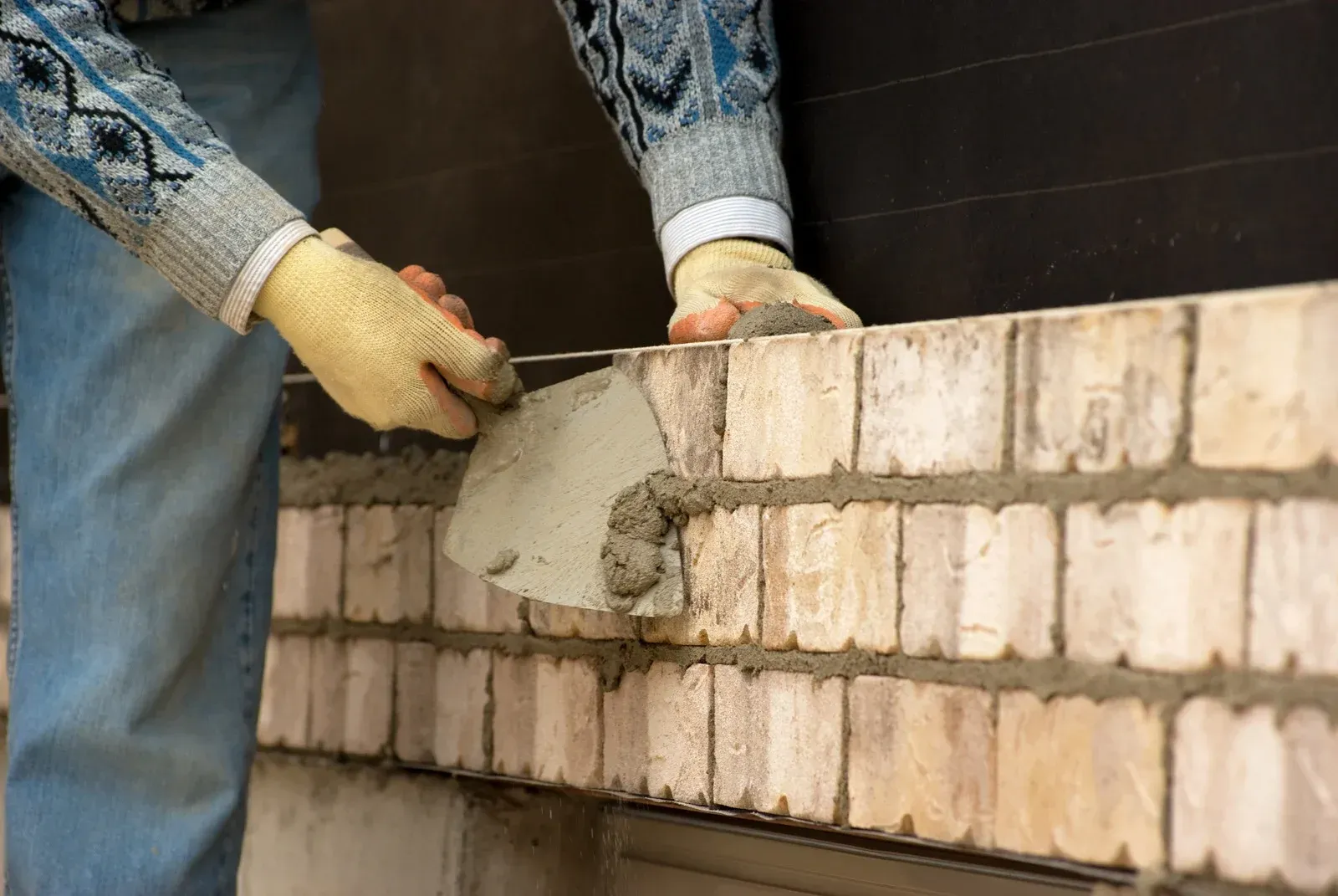Worker spreading mortar on a brick wall with a trowel