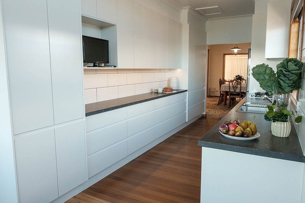A kitchen with white cabinets and a black counter top — Flow Kitchens in Taree South, NSW