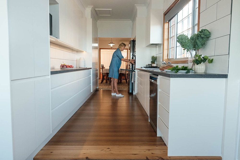 A Man is Standing in a Kitchen Cleaning the Floor — Flow Kitchens in Gloucester, NSW