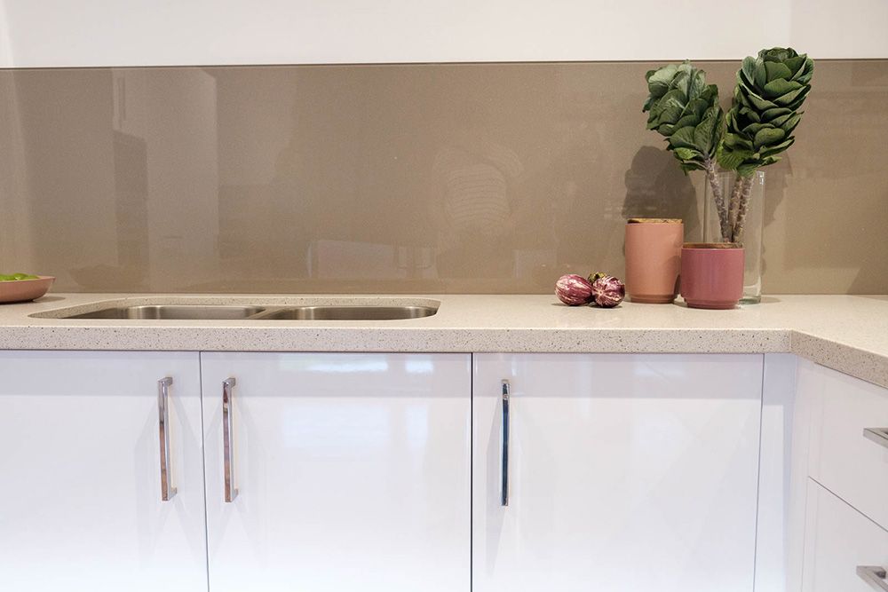 A kitchen with white cabinets, a sink, and a plant on the counter— Flow Kitchens in Forster, NSW