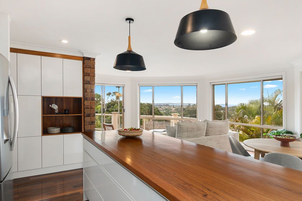 Kitchen With Wooden Countertop, White Cabinets, and Large Windows Overlooking a Scenic View — Flow Kitchens in Taree South, NSW
