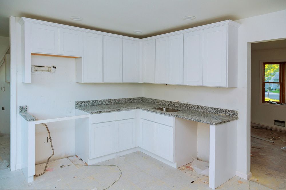 A Kitchen Under Construction With White Cabinets and Granite Counter Tops — Flow Kitchens in Harrington, NSW