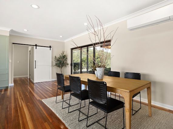 Dining Room With Wooden Table and Chairs, Hardwood Floor, Rug, Sliding Glass Doors — Flow Kitchens in Taree South, NSW
