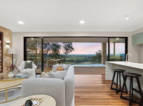 Living Room With Large Sliding Doors Open to a Scenic View, Wooden Floors, and Kitchen Bar — Flow Kitchens in Taree South, NSW