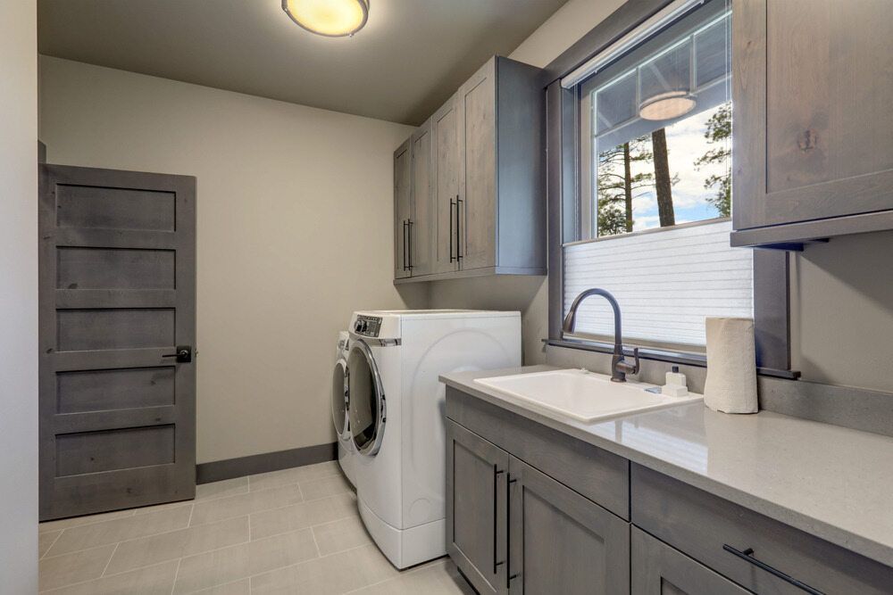 A Laundry Room With a Washer and Dryer, Sink, Cabinets and a Window — Flow Kitchens in Old Bar, NSW