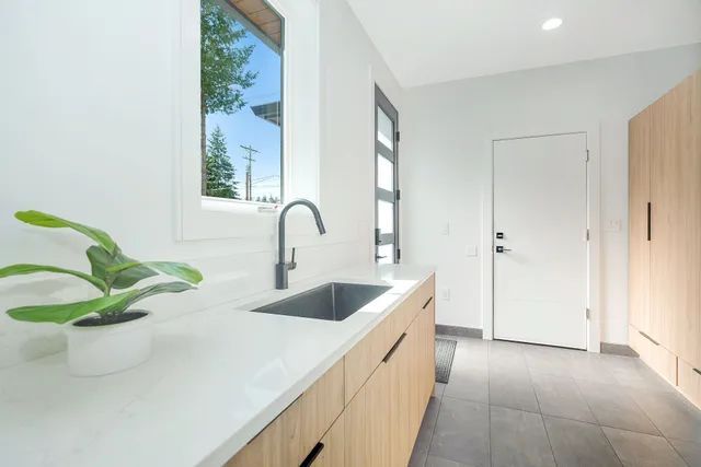 A laundry with a sink and a potted plant on the counter — Flow Kitchens in Taree South, NSW