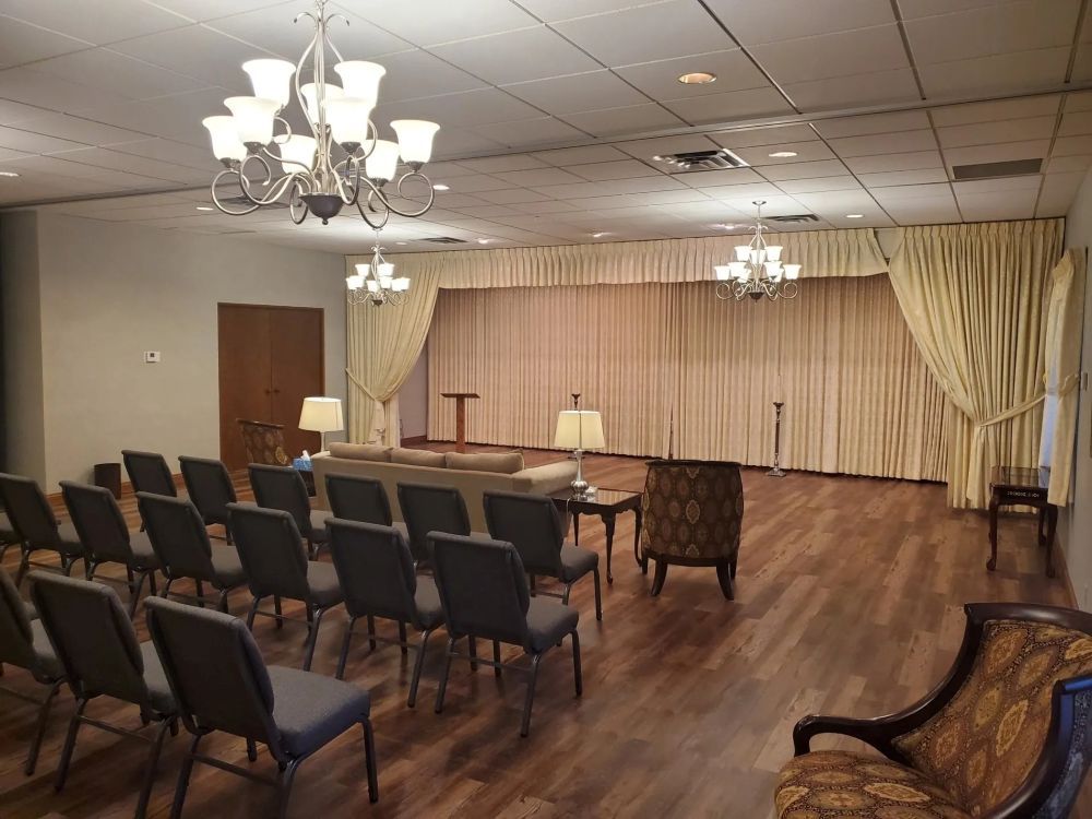 Interior of a funeral home chapel with chairs facing a draped stage.