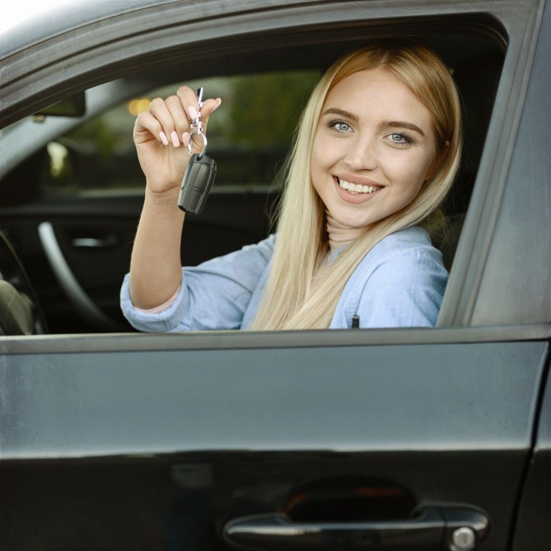 A woman is sitting in a car holding a car key