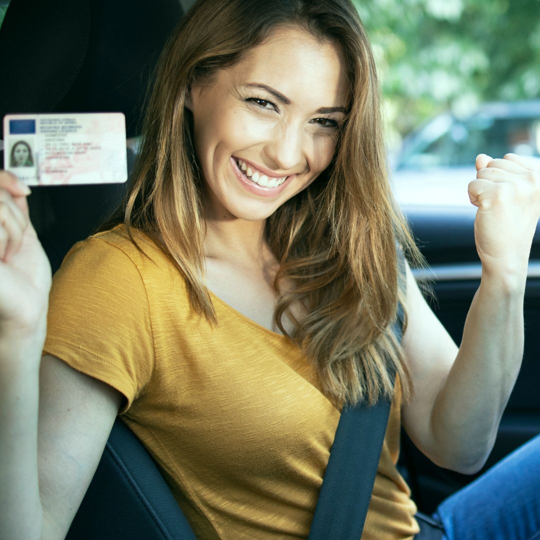 A woman in a yellow shirt is holding a drivers license
