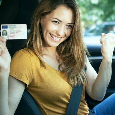 A woman in a yellow shirt is holding a drivers license