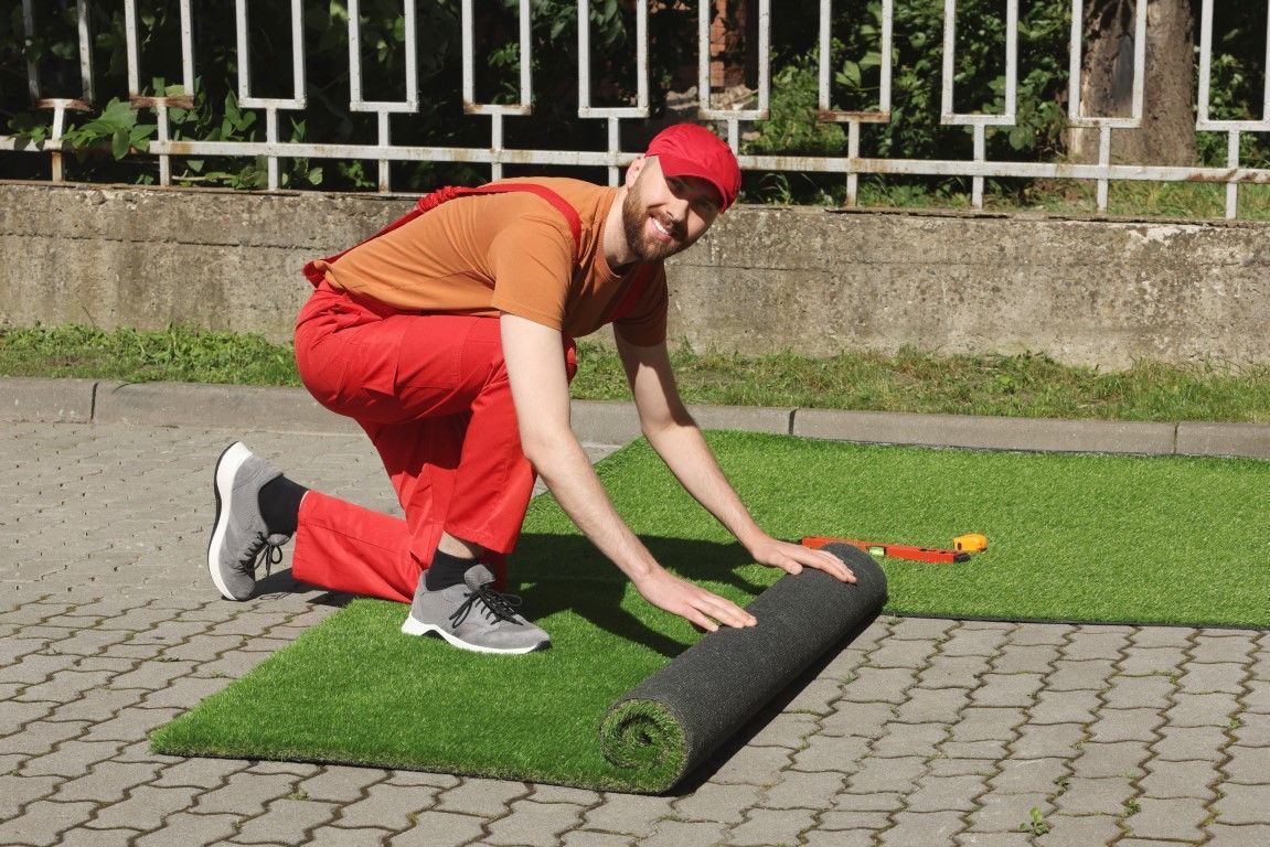 Modern side yard landscape path with fake grass and pebbles.