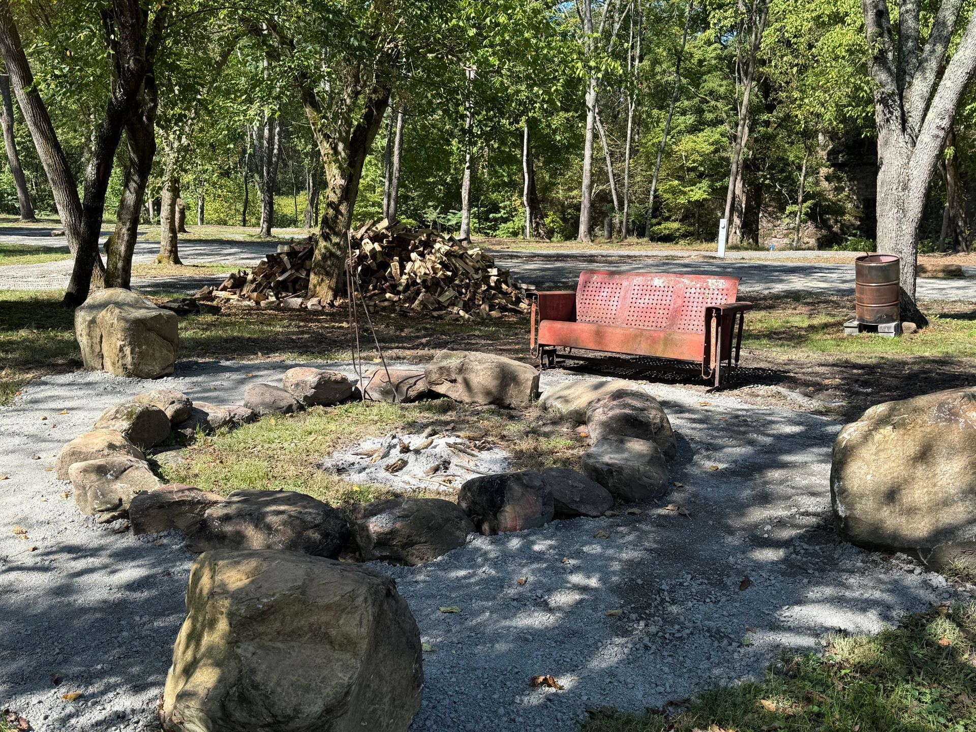 A red couch is sitting in the middle of a fire pit surrounded by rocks.
