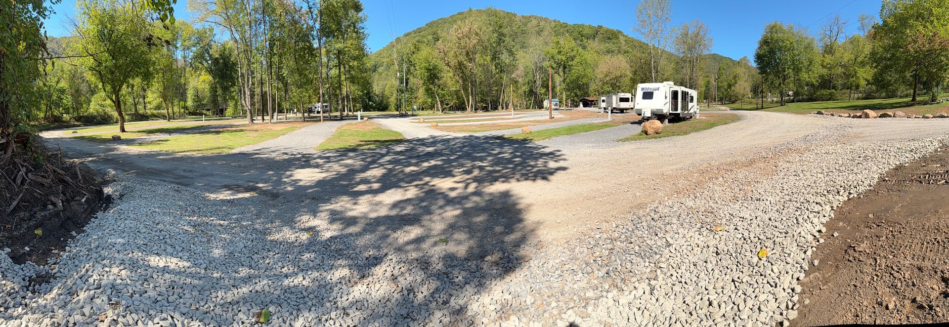 A rv is parked in the middle of a gravel road in a park.