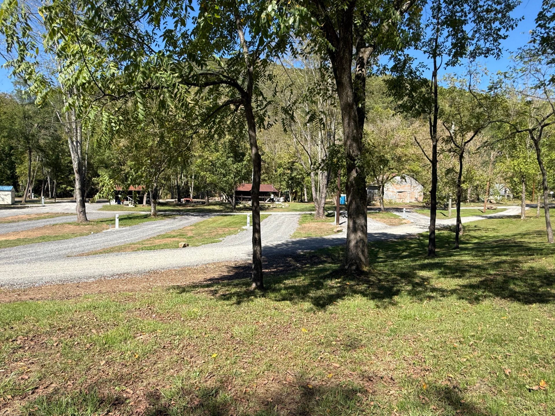 A park with a lot of trees and grass and a dirt road.