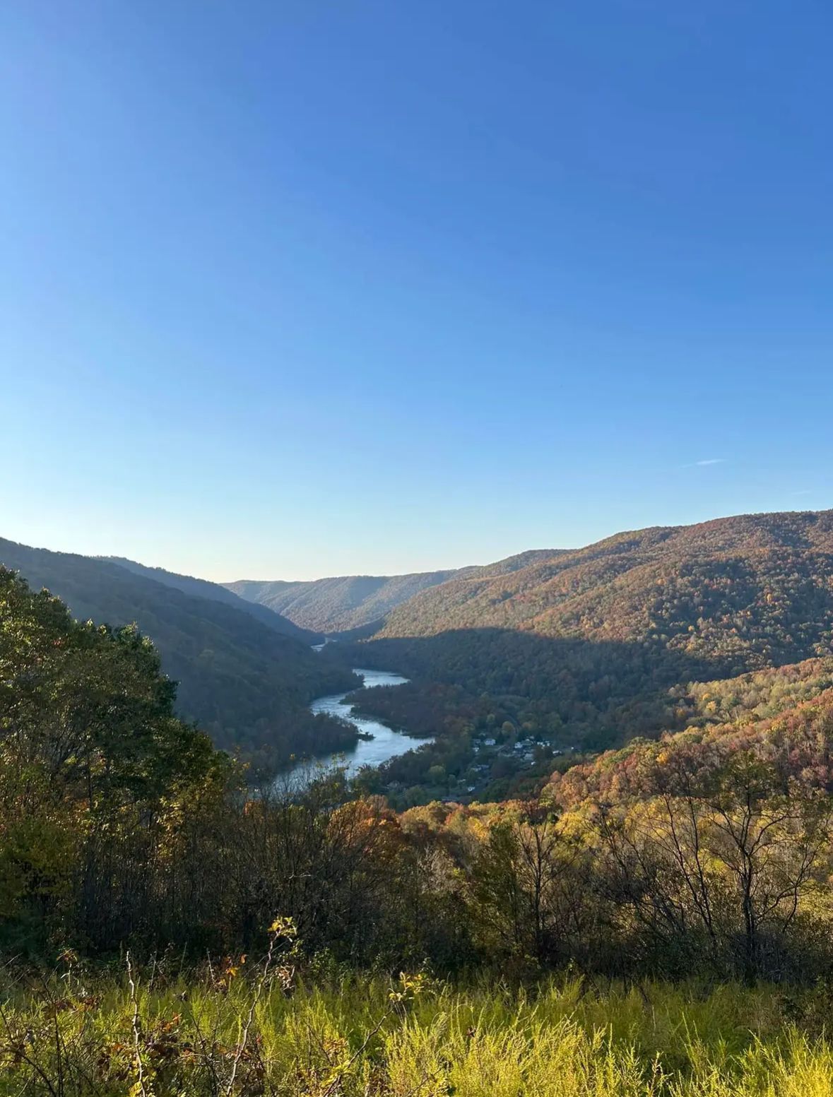 A river flowing through a valley surrounded by mountains on a sunny day.