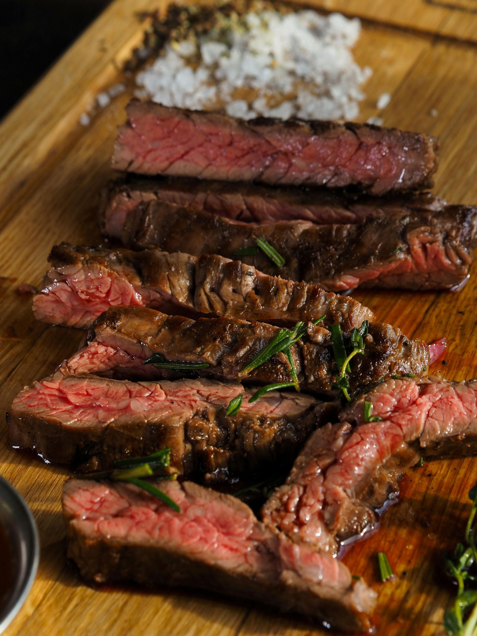 A close up of a steak on a wooden cutting board.